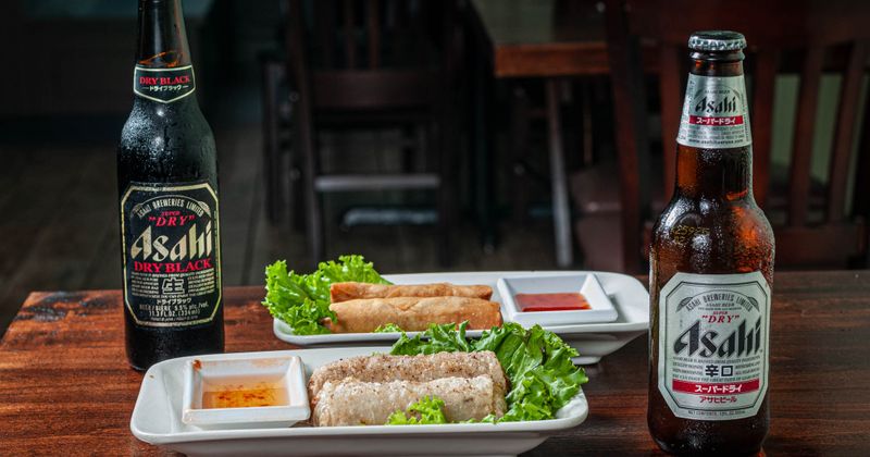 Chicken and Pork Egg Rolls plates and two bottles of beer on the table, side view