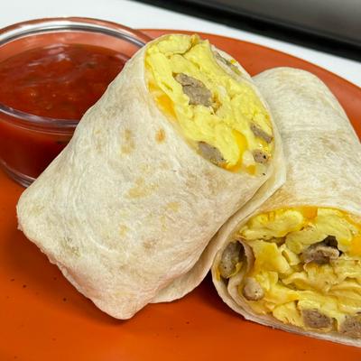 Scrambled egg and meat wrap served with a red sauce.