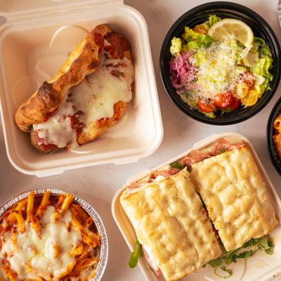 An assortment of Italian takeout dishes including panini, pasta, sub, and salad.