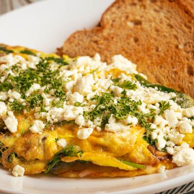 Stuffed Omelette topped with crumbled cheese and herbs, served with toast.