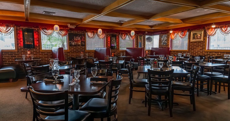 Interior with dark wooden furniture, red leather booths, brick walls and soft lighting
