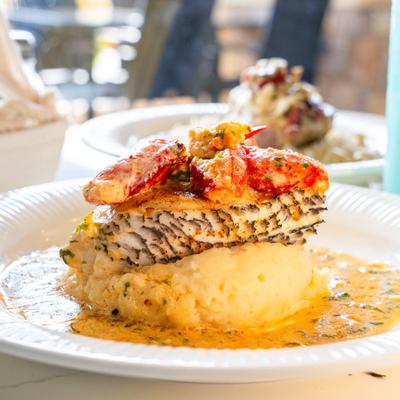 Grilled fish fillet with lobster served over mashed potatoes.
