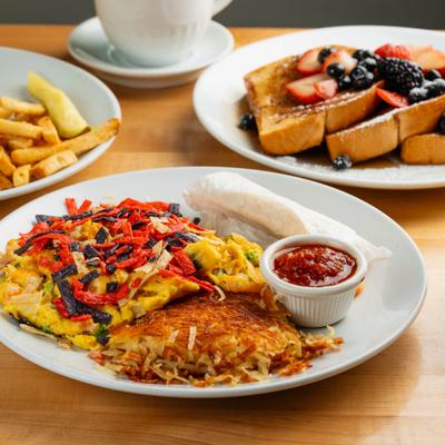 Migas served alongside french toast, plate of fries and a drink.