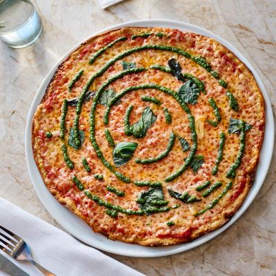Pizza with tomato sauce, cheese, basil, and pesto sauce.