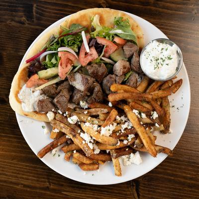 Lamb gyros served with Greek fries, tzatziki, and mixed salad, overhead view.