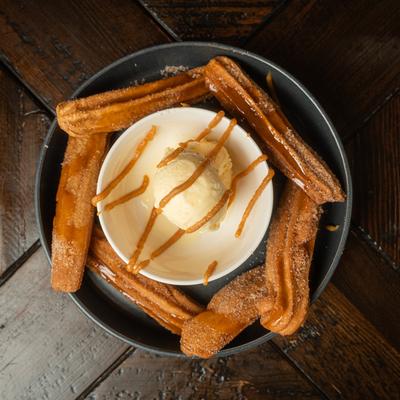 Churros served with rice pudding ice cream, drizzled with caramel syrup.