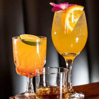 Two cocktails beside a glass of neat whiskey.