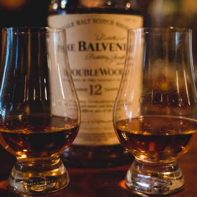 Two Glencairn glasses with straight whiskey and a partially visible whiskey bottle.