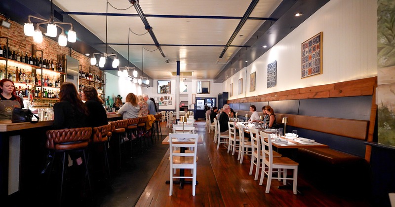 Warm and cozy restaurant interior, dining area, and bar area, guests enjoying their food and drinks