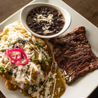 Chilaquiles Verdes served with skirt steak and black beans.