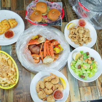 Assorted seafood dishes served alongside sliders and fries.