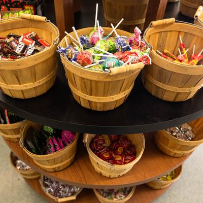 Multi-tiered display stand filled candies and chocolates in small wooden buckets.
