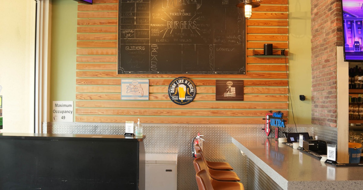 Interior of a bar with a chalkboard menu, bar stools and industrial decor.