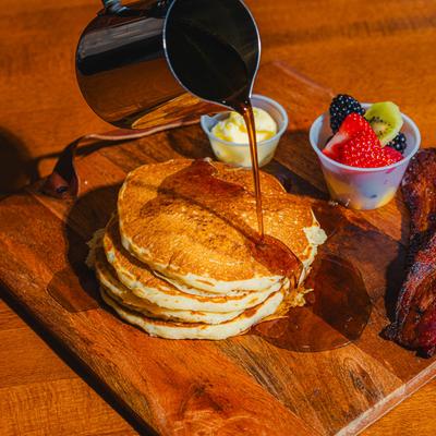 Maple syrup being poured over panacakes.