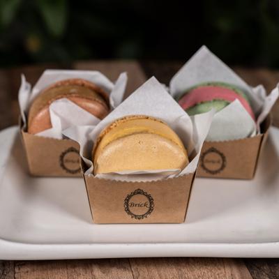 Macaron ice cream sandwiches presented in individual paper cups.