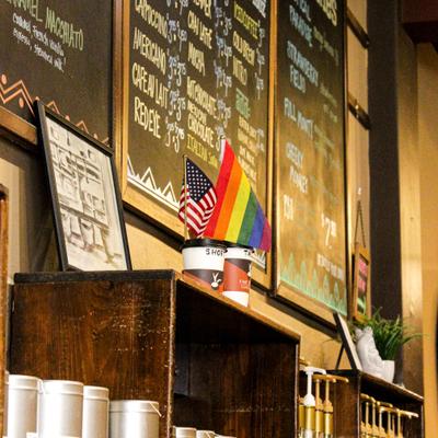 Cafe counter with menu boards and small American and rainbow flags.