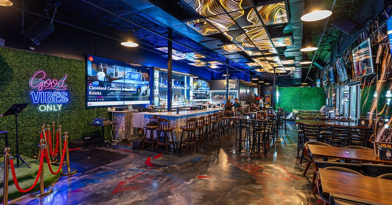 Interior of modern sports bar and entertainment venue with a long bar and dining tables and chairs