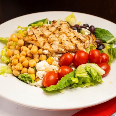 Grilled chicken salad with lettuce, chickpeas, cherry tomatoes, olives, and feta cheese