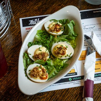 Deviled eggs topped with whole grain mustard and chives on a bed of lettuce.