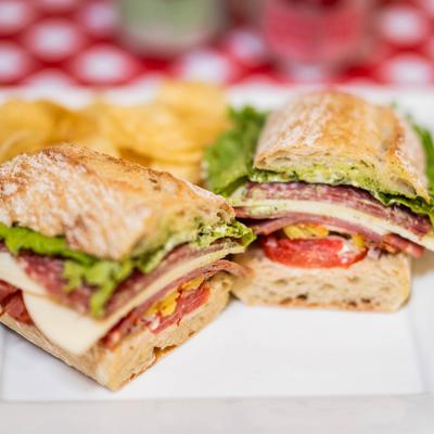 The Italian Club sandwich featuring layers of Italian meats , cheese and a side of chips.