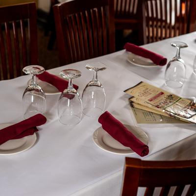 Table set with white tablecloth, white plates with red napkins, and glasses.