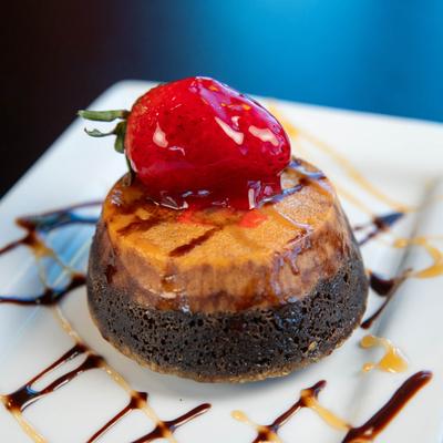 A rich chocolate and caramel flan topped with a glossy strawberry.