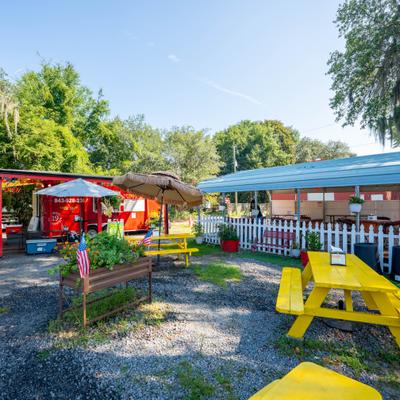 Outdoor dining area with bright yellow picnic tables and gravel ground cover.