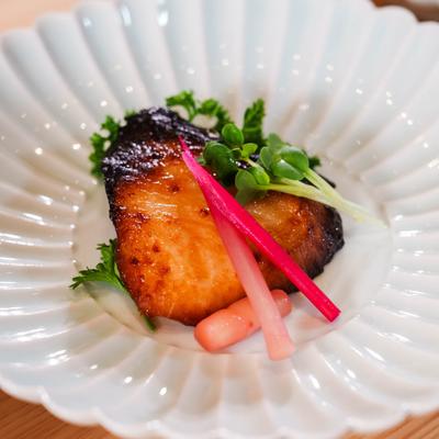 Grilled fish fillet garnished with microgreens and pickled vegetables.
