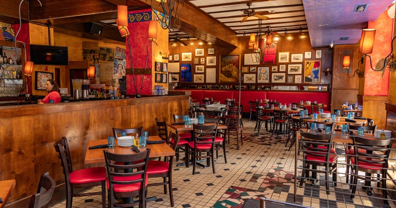 Interior view of a restaurant featuring wooden furnishings, red cushioned chairs