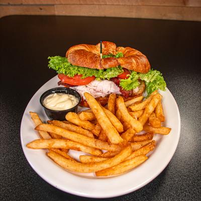 Turkey club croissant paired with fries and a dipping sauce.