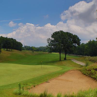 A lush golf course under a bright blue sky with fluffy clouds.