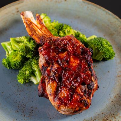 Grilled pork chop with sauce and broccoli.