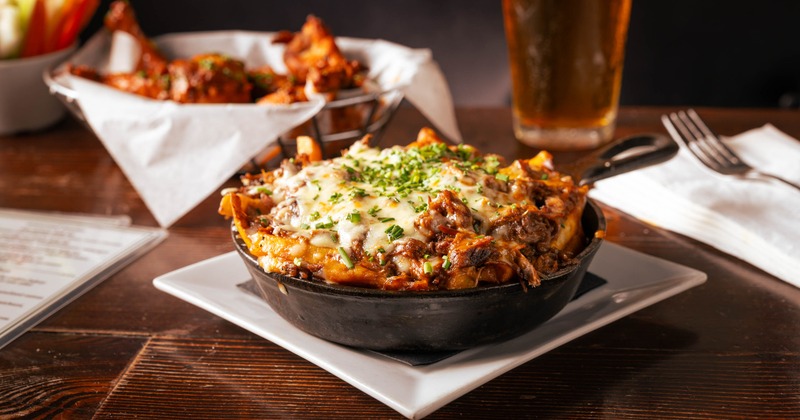 Short Rib Poutine served in a cast-iron skillet, topped with melted cheese