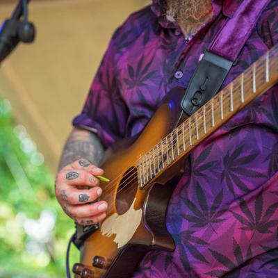 A musician strumming an electric guitar on a stage, close up.