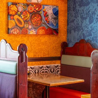 Booth seating featuring yellow walls and a painting of assorted Mexican dishes.