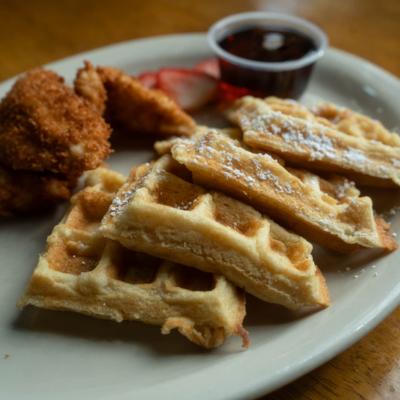 Chicken and waffles with warm syrup on the side.