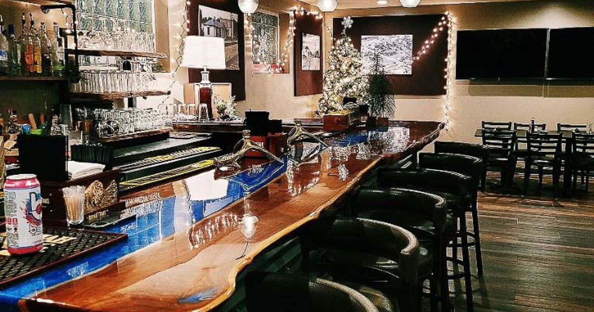 Warmly lit bar with a polished wooden counter, pendant lights and festive decorations