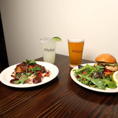 plate of Grilled salmon and plate of Grilled Chicken sandwich with house salad , Beer and margarita.