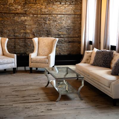 Industrial lounge room featuring brick walls, armchairs, and glass coffee-table.