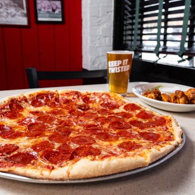 Pepperoni pizza accompanied with beer on a table inside.