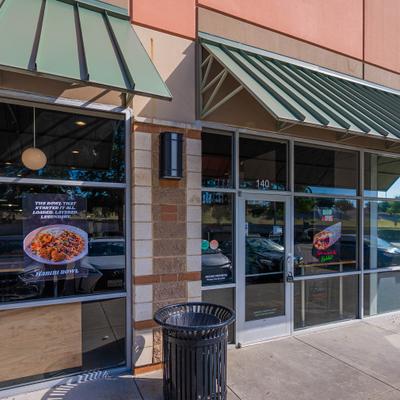 Storefront with green awning, entrance and window signage.