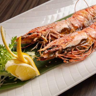 Grilled tiger prawns with lemon and herb garnish.