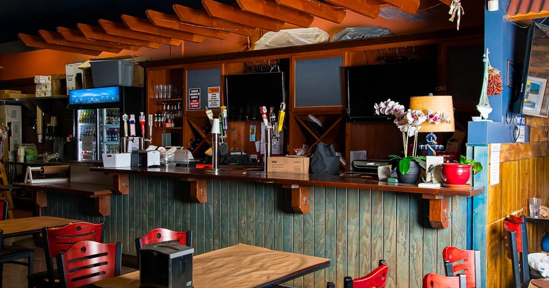 Interior, tables and chairs ready for guests with bar in the back