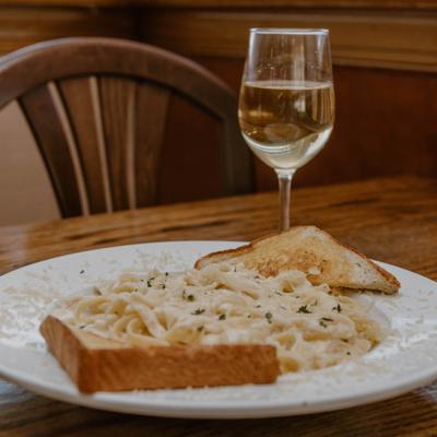 Fettuccine Alfredo served with garlic bread and a glass of wine.