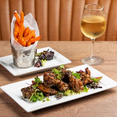 Chicken wings, fries, and a glass of white wine.