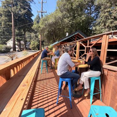 People sitting and talking on an elevated wooden outdoor patio.