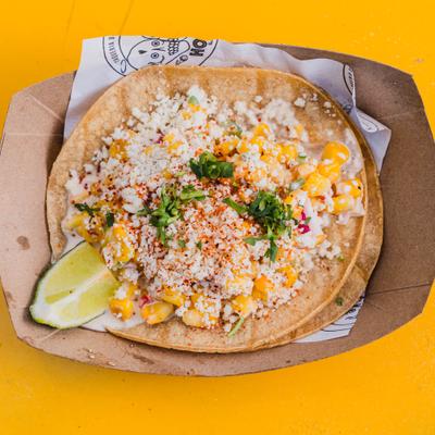 Esquite taco topped with corn, crumbled cheese and served with a lime wedge.