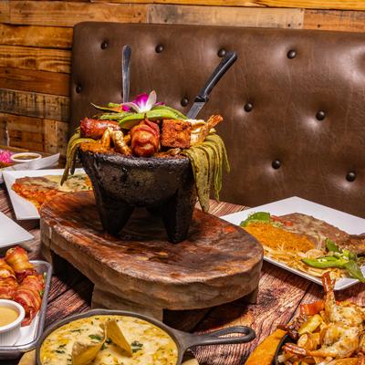 Mixed molcajete bowl on a table surrounded by Mexican dishes.