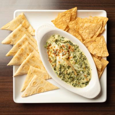 Spinach and artichoke dip served with naan triangles and tortilla chips.