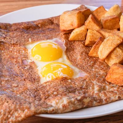 Juventus crepe with two fried eggs, ham, cheese, and potatoes.